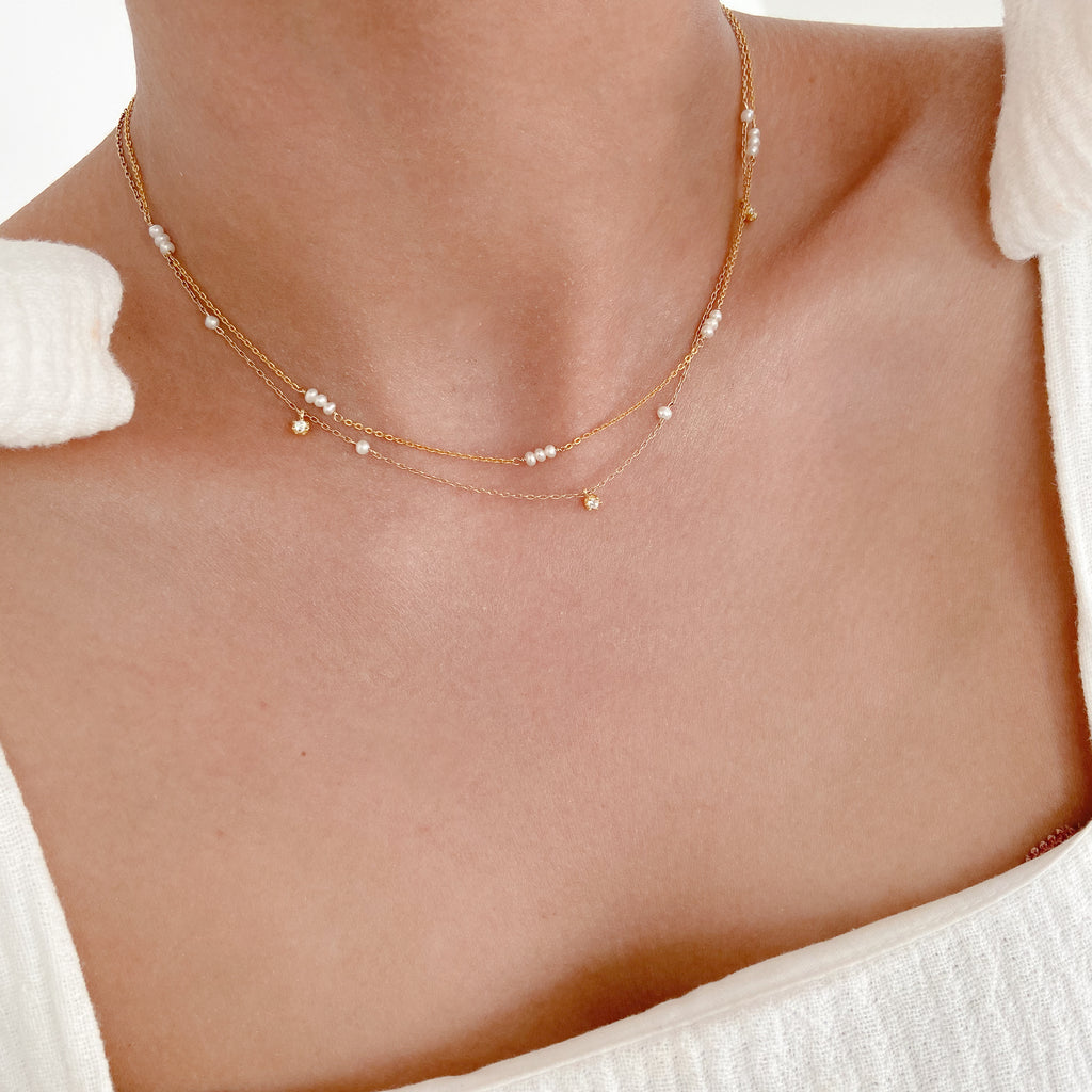 pearl necklace layered with gold chain on female