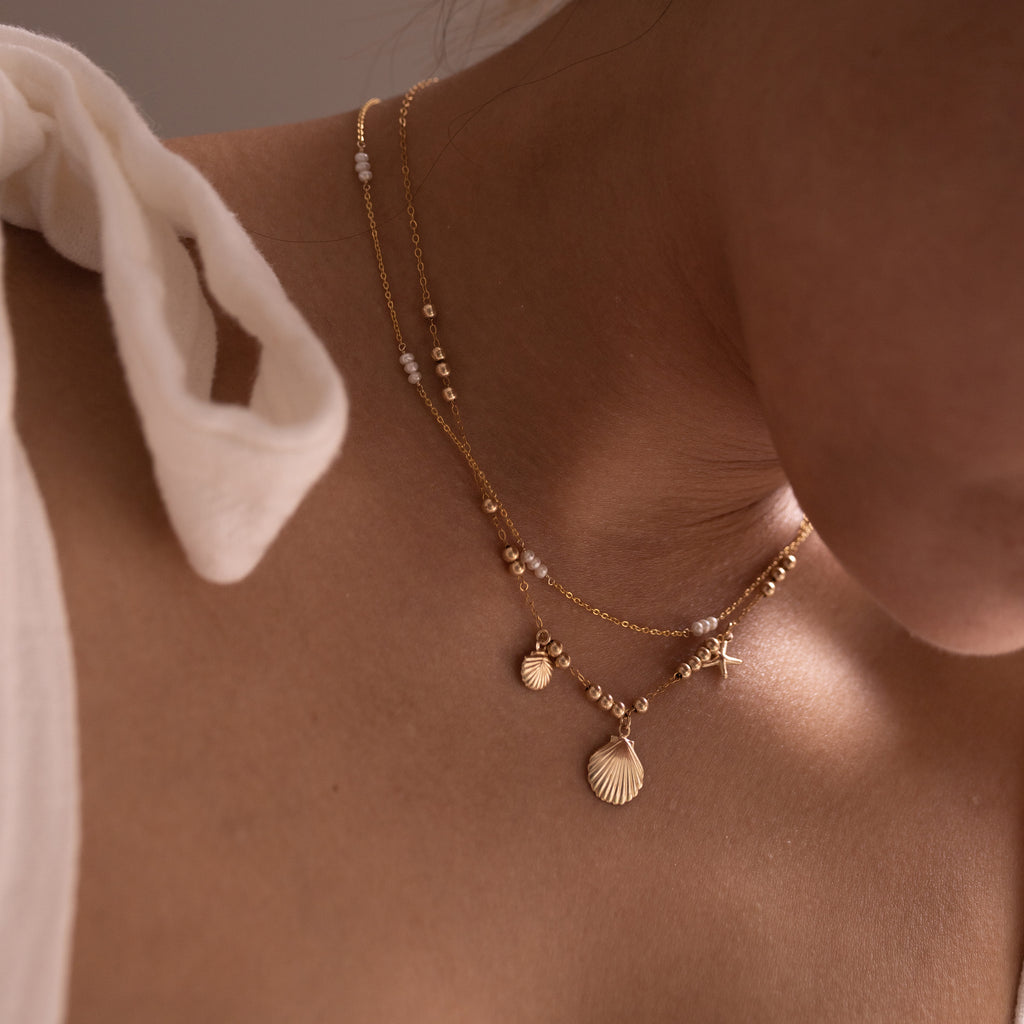 dainty necklaces layered with pearls and seashells